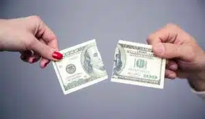 Concept Image Of A Female And Male Hand Dividing Money Over Gray Background