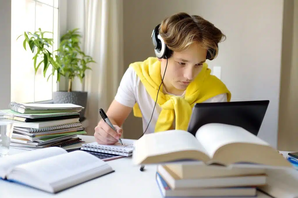 Tennager Boy Study At Home. Online Education And Distance Learning For Children. School Boy Doing His Homework Using Gadgets. Lectures And Lessons On The Internet For High School Students